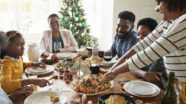 Woman cutting meat for family and friends on table 